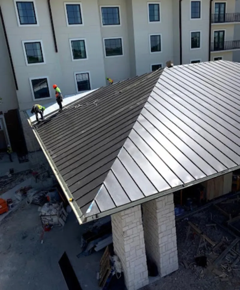 Crew installing standing seam metal roof panels on a commercial project in Old Forge